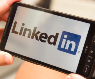 Holding a smartphone with LinkedIn Logo