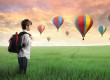 Boy standing in field with hot air balloons