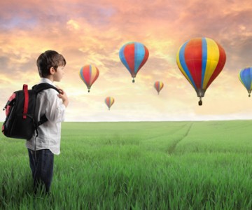 Boy standing in field with hot air balloons