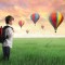 Boy standing in field with hot air balloons
