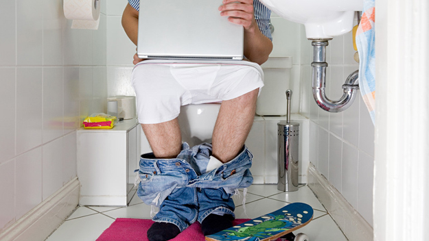 Man on toilet using laptop