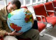 Man sleeping on globe in airport