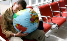 Man sleeping on globe in airport