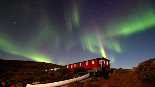 Aurora borealis glows over a hut