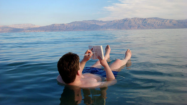 Man reading book while floating in Dead Sea