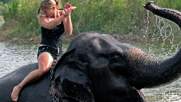 Woman riding an elephant through a river