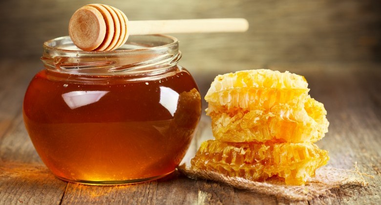 jar of honey with honeycomb on wooden table