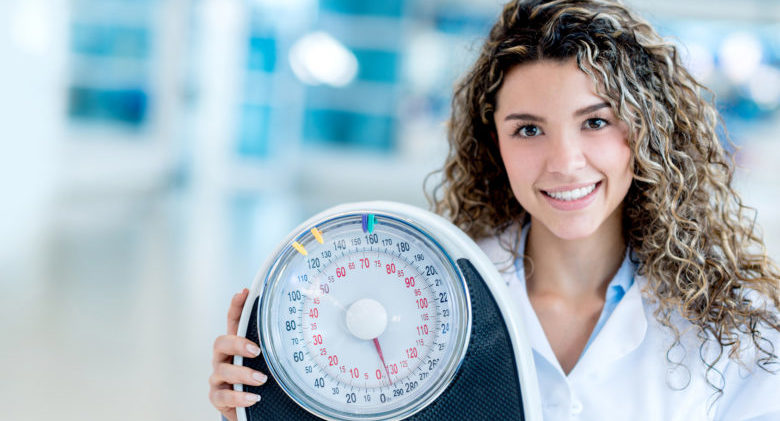 Female nutritionist at the hospital holding a weight scale