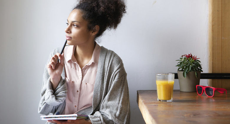 Portrait of a young woman sitting at home with pen and paper