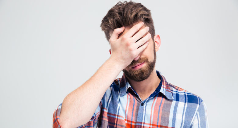 Portrait of upset man covering his face with hand isolated on a white background