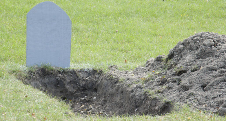 Shallow open grave with blank tombstone