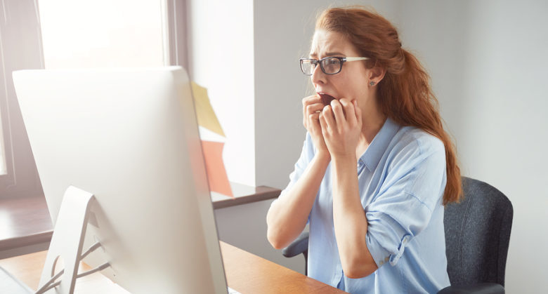 Stressed shocked businesswoman sitting at the table in front of computer in the office looking stunned mouth wide open. Negative human face expressions emotions body language reaction