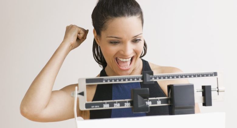 Hispanic woman cheering on scale