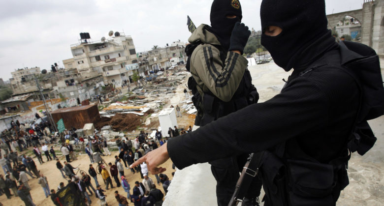 KHAN YOUNIS, GAZA STRIP - MARCH 27: Islamic Jihad militants watch over a crowd from atop a mosque during the funeral of Haithem Arafat, 23, who was killed on Friday in clashes with Israeli soldiers, on March 27, 2010, Khan Younis, Gaza Strip. Two Israeli soldiers and at least one Palestinian militant were killed Friday, during clashes on the Israel/Gaza border. (Photo by Warrick Page/Getty Images)