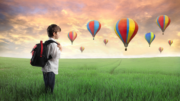 Boy standing in field with hot air balloons