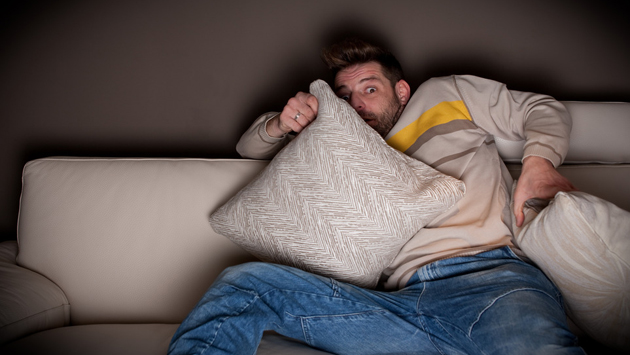 Frightened man watching a horror movie