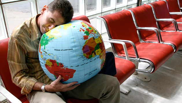 Man sleeping on globe in airport